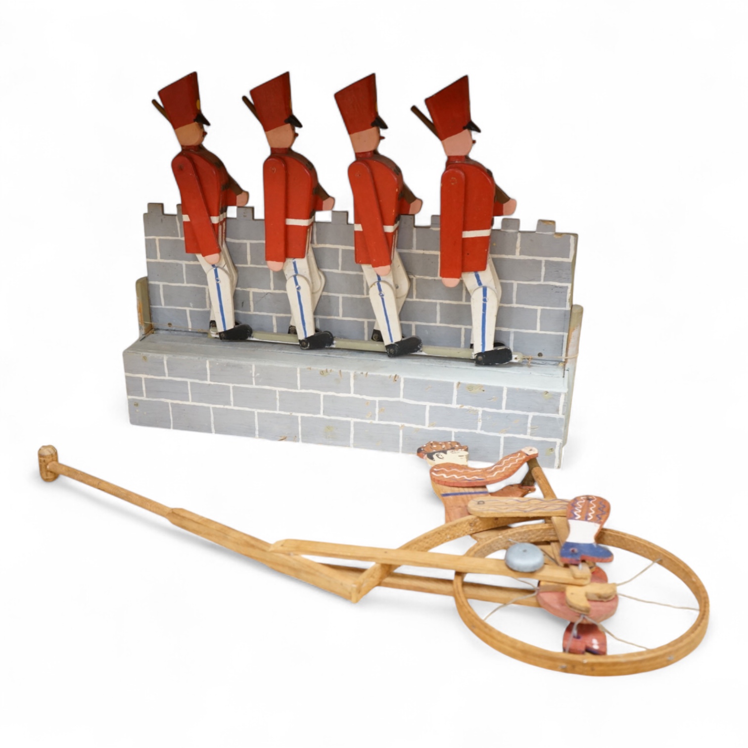 A decorative painted wood articulated ‘soldiers’ toy and another penny farthing toy